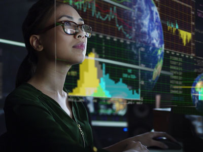 Woman looking up with graphics around on a screen (globe, graphs, line charts)