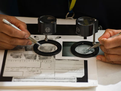 Fingerprint specialist examines fingerprints on a card